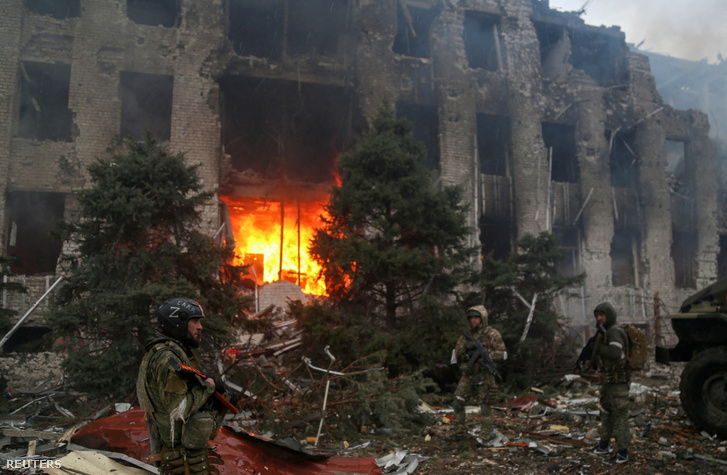 Orosz erőkhöz tartozó katonák az Azovstal Vas- és Acélgyár lerombolt adminisztrációs épülete előtt 2022. április 21-én