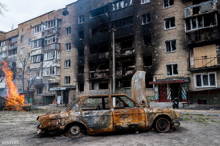 Egy megrongált autó és egy leégett épület Kijevben Ukrajnában 2022. április 19-én