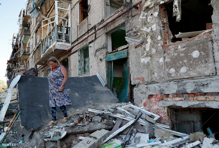Egy helyi lakos egy megrongálódott lakóház előtt Mariupolban 2022. április 28-án
