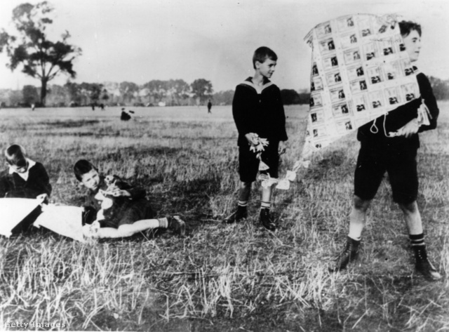 Német gyerekek értéktelen papírmárkából készült sárkánnyal játszanak