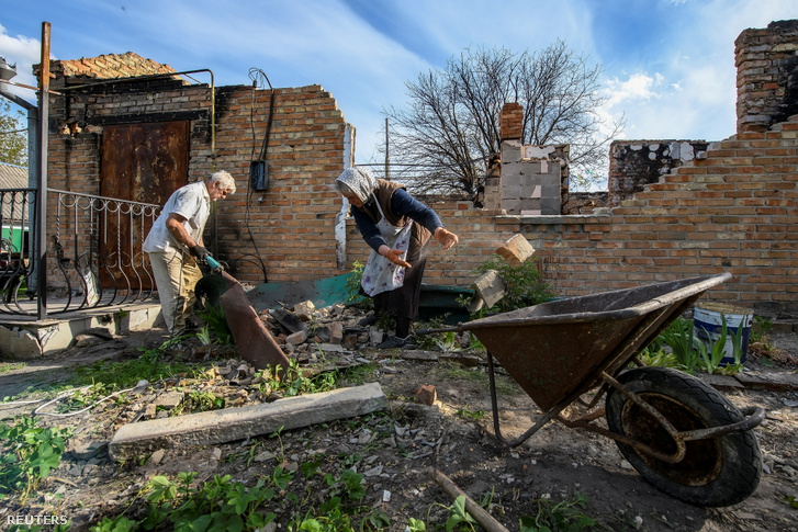 Helyi lakosok szedik össze a törmelékeket egy lebombázott lakóháznál a Zahalci faluban Ukrajnában 2022. május 13-án
