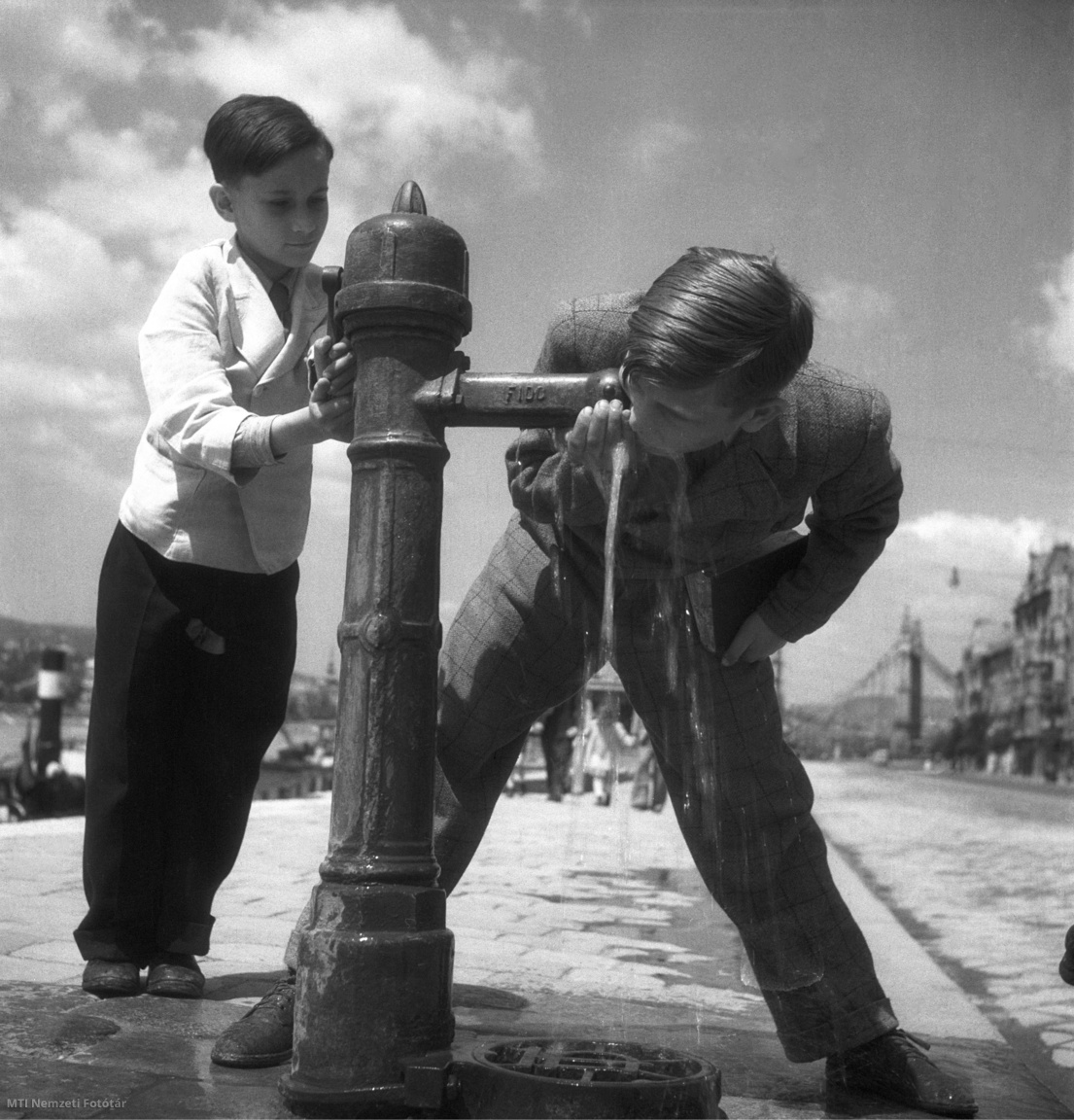 Budapest, 1948. május 19. Fiúk isznak egy kútból a Szabadság híd pesti hídfőjének közelében