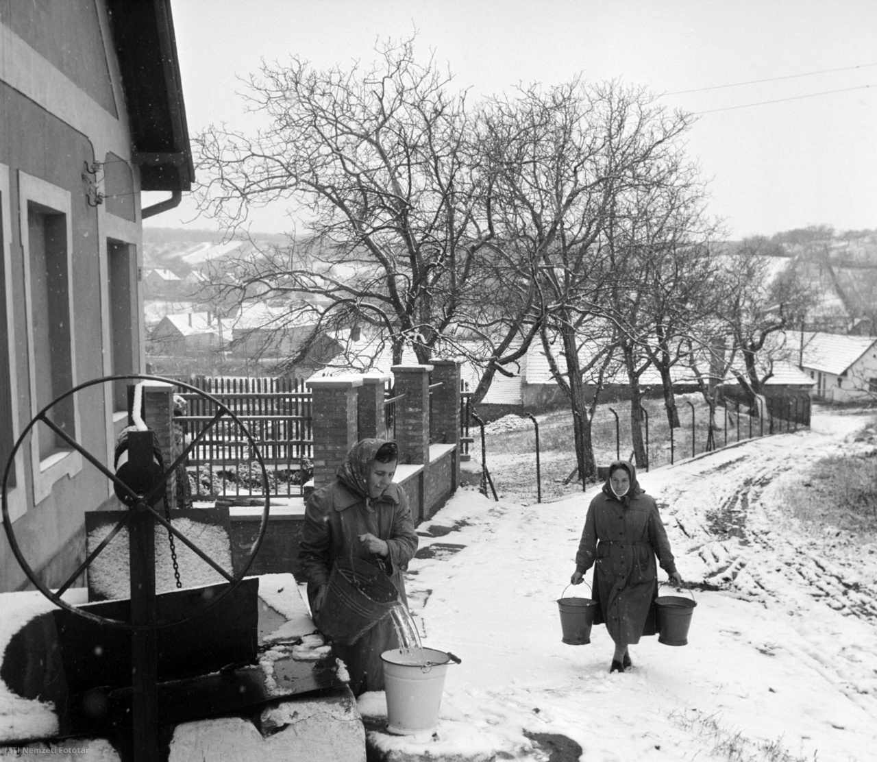 Pilisborosjenő, 1964. december 3. Asszonyok hordják a vizet a kerekes kútból az első havazás reggelén