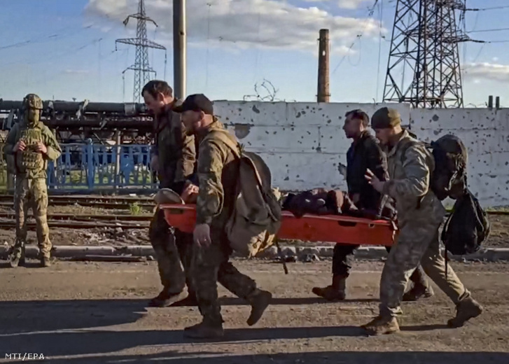 Az orosz védelmi minisztérium sajtószolgálata által videófelvételről készített képen ukrán katonák viszik sebesült társukat a mariupoli Azovsztal acélmű területén 2022. május 17-én