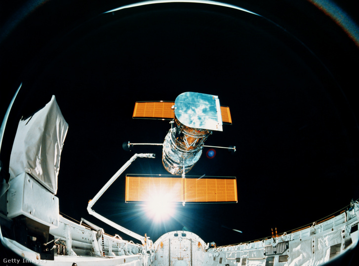 Egy űrsikló raketere felett lebeg a Hubble az 1990-es évek elején