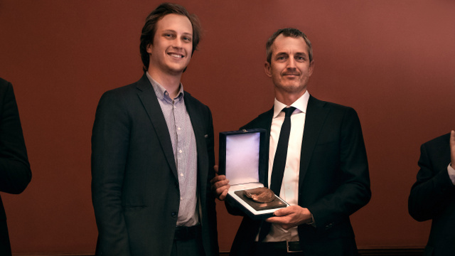 Matthew Gentzkow, az amerikai közgazdász (jobbra) átveszi a 2021. Neumann János-díjat a Rajk Szakkollégium Diákbizottságának titkárától, Velkey Artúrtól
