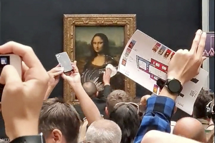 Biztonsági őr takarítja a tortakrémet Leonardo da Vinci olasz művész Mona Lisa című festményének védőüvegéről a párizsi Louvre múzeumban 2022. május 30-án