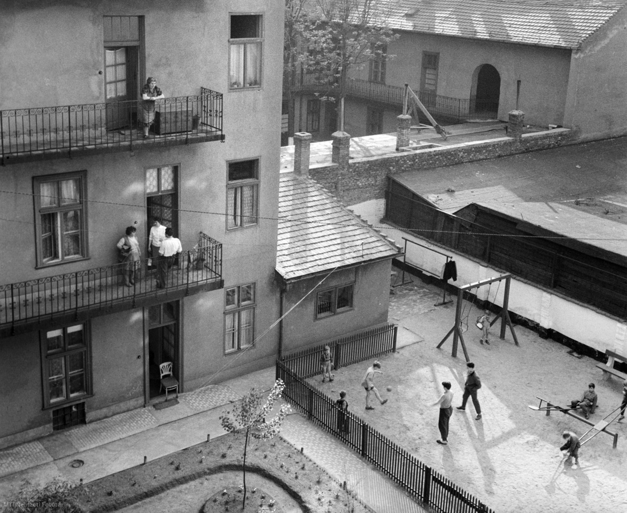 Budapest, 1963. május 9. A függő körfolyosón, gangon beszélgetnek a délelőtti napsütésben a Lehel út 32. szám alatti bérház lakói és a gyerekek játszanak az udvaron. A ház nemrég ünnepelte építésének 50. évfordulóját. Ebből az alkalomból tatarozták és udvarán a ház lakói társadalmi munkában parkot és játszóteret létesítettek.
