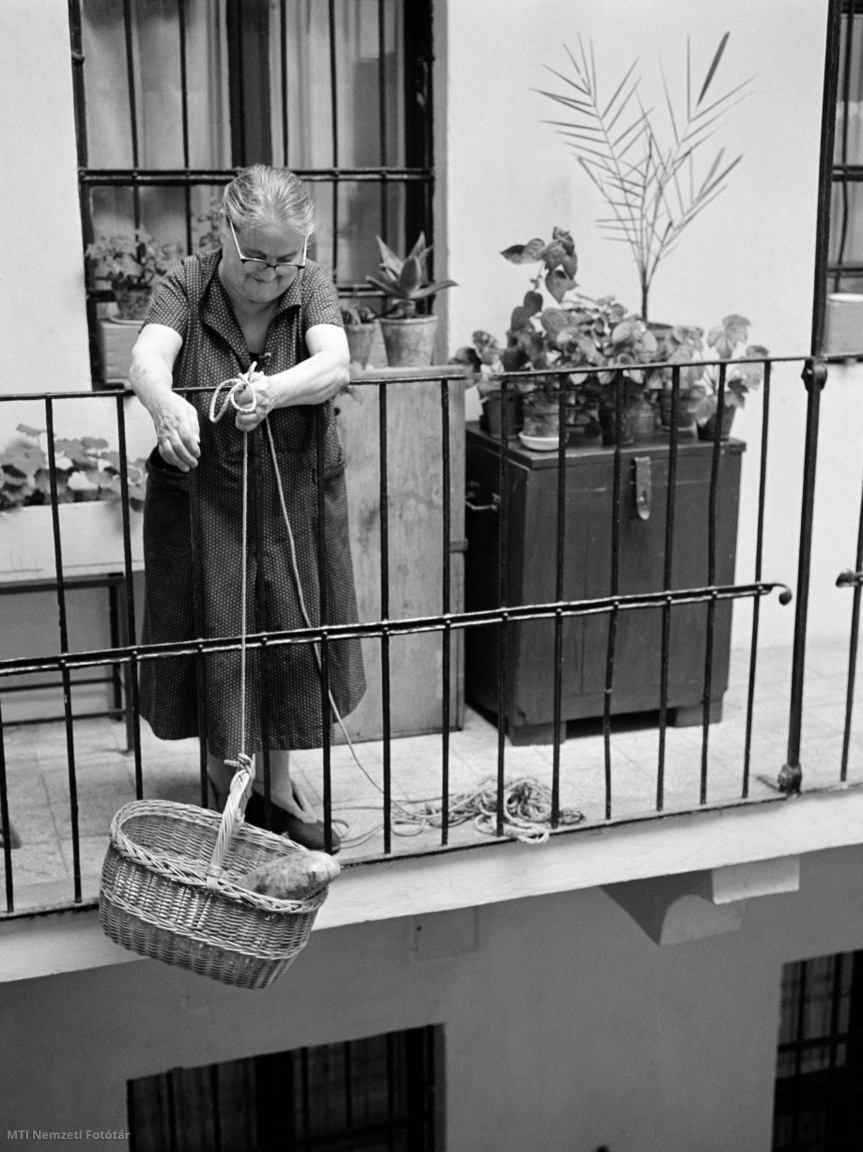 Budapest, 1964. szeptember 2. Idős asszony egy kosárban (kosárlift) húzza fel a kenyeret a Váci utca és Régiposta utca sarkán álló nemrég renovált épület udvaráról lakásához az emeleti körfolyosóra (gang). A régi belvárosi házak udvarai egy letűnt világot idéznek fel. A boltíves, tornácos házak udvarán valamikor istálló, esetleg gémeskút is állt, és nem egynek a közepén a régi pesti városfal húzódik végig.