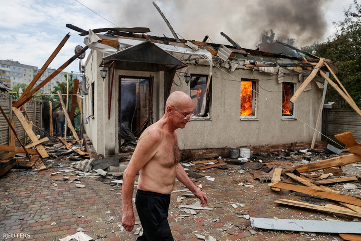 Egy helyi lakos sétál szomszédja ágyúzás miatt lángoló háza előtt 2022. június 2-án Luhanszk régióban