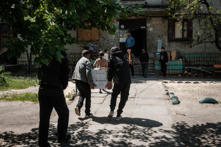 A lakosok élelmiszert kapnak, miközben önkéntesek naponta szállítanak egy humanitárius segélyosztó központ raktárából a kelet-ukrajnai Szeverodonyeckben, 2022. május 7-én