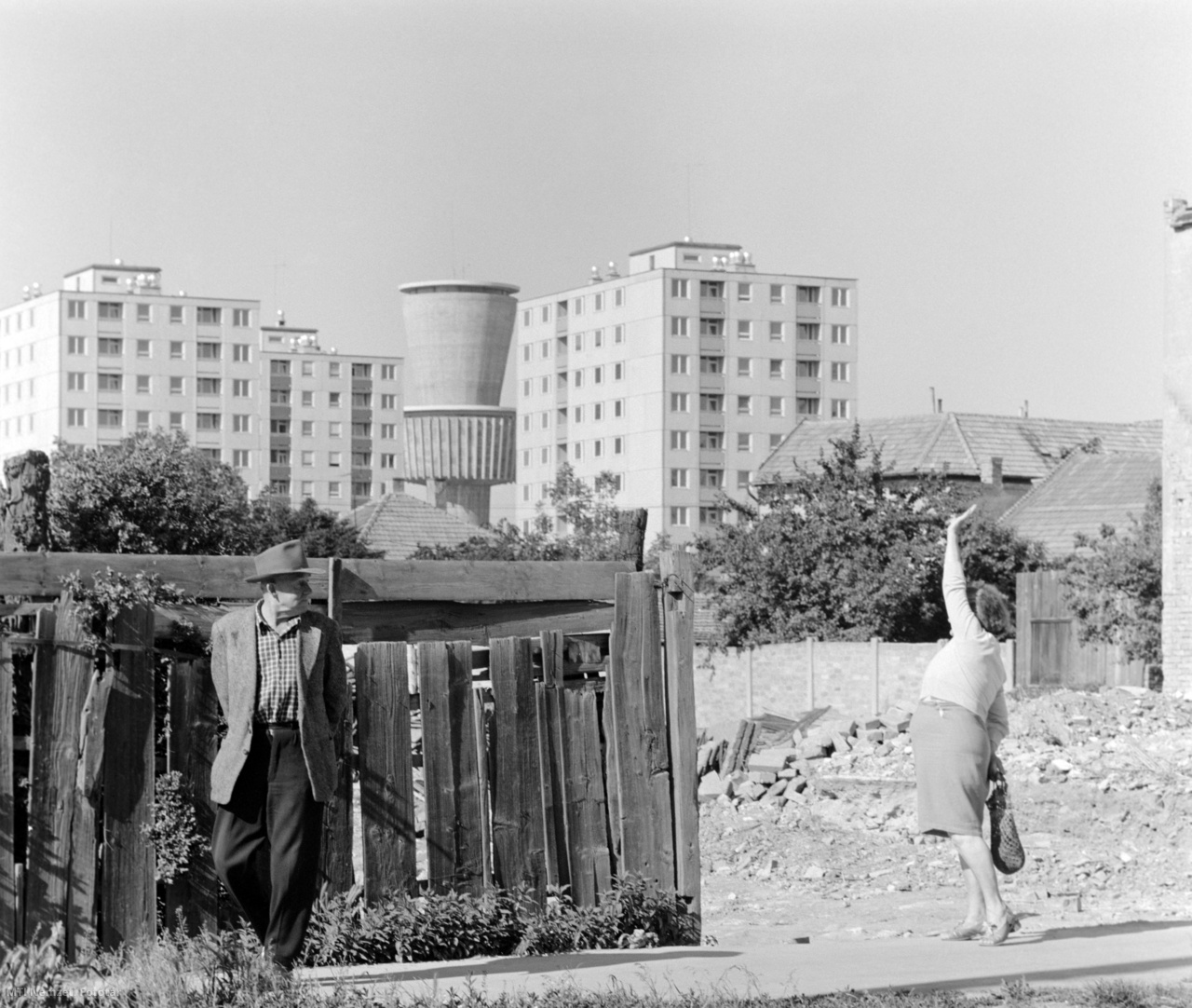 Szeged, 1973. május 29. A régi, földszintes házak maradványai előtt egy férfi és egy integető nő Szeged új lakónegyedénél, a Tarján városrészen épülő lakótelepen. Háttérben a modern víztorony.