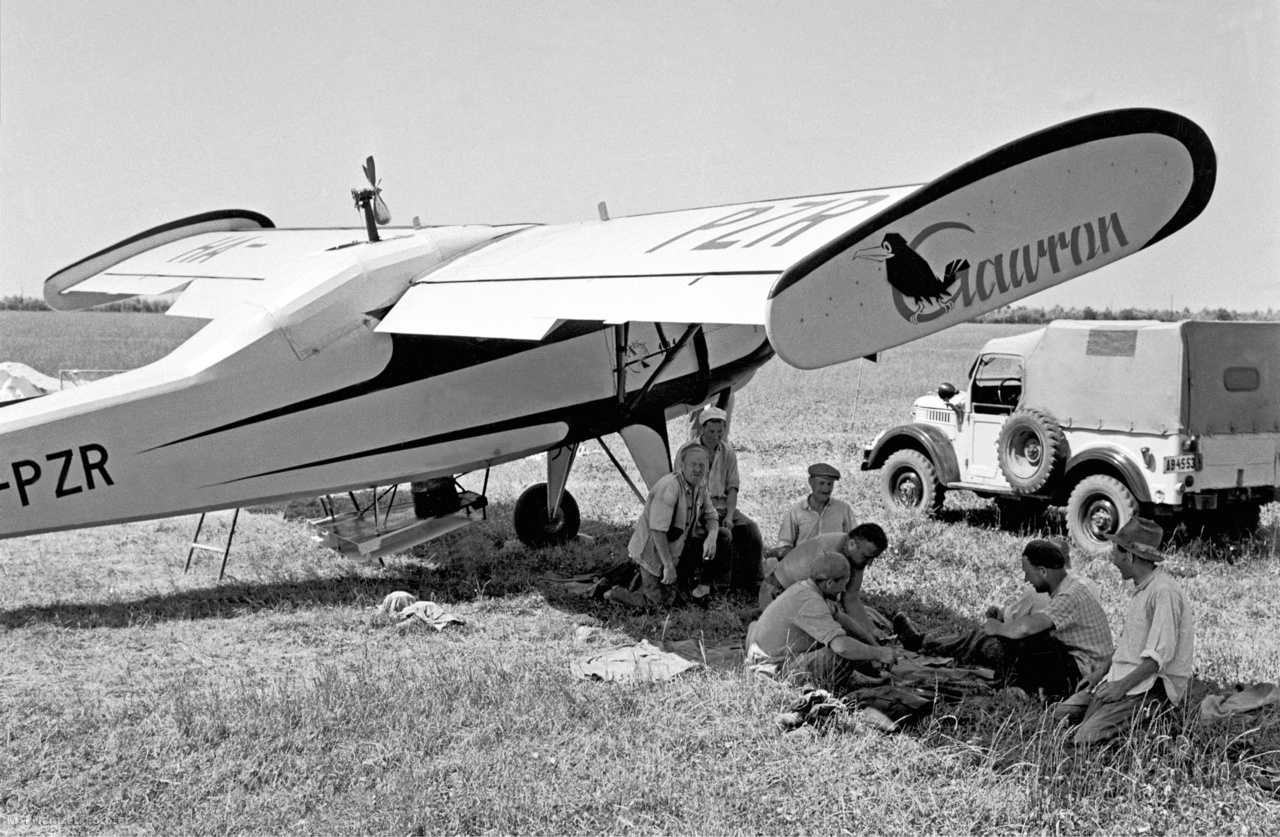 Győr-Moson-Sopron megye, 1961. július 1. Az ebédszünetben ultiznak a repülőgép-kiszolgálók. Egyszerre öt mázsa műtrágyát – két hold trágyázására elegendő mennyiséget – töltenek a lengyel gyártmányú PZL–101-es Gawron, Holló mezőgazdasági repülőgépbe a Lajta-Hanság Állami Gazdaságban, hogy az őszi gabona- és kukoricavetés alá mintegy 30 ezer holdon szórják ki a műtrágyát. A felvétel készítésének pontos helye ismeretlen.