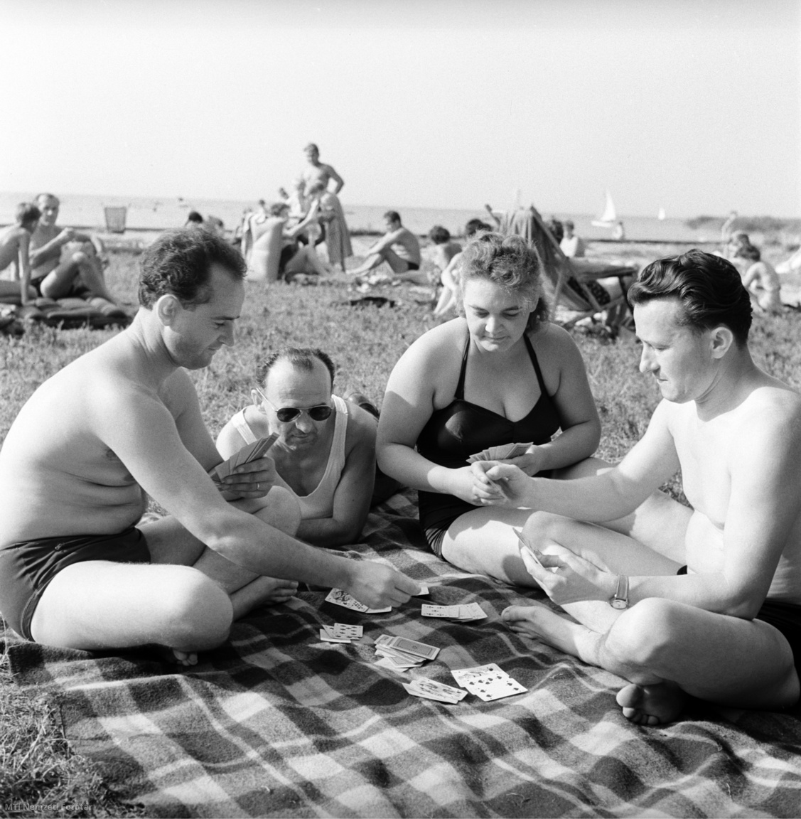 Magyarország, 1962. augusztus 4. A Helvéciai Állami Gazdaság dolgozói üdülnek, kártyázva pihennek a Balaton partján. A felvétel készítésének pontos helye ismeretlen.