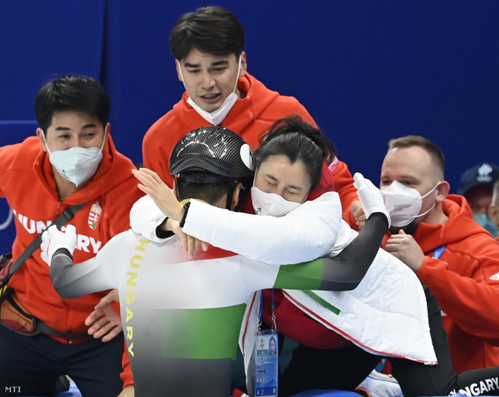 A győztes Liu Shaoangot (háttal) köszöntik, jobbról Csang Csing Lina vezetőedző (j2) és Liu Shaolin Sándor (k), Liu Shaoang testvére a férfi rövidpályás gyorskorcsolyázók 500 méteres versenyének döntője után a Fővárosi Fedett Stadionban a pekingi téli olimpián 2022. február 13-án