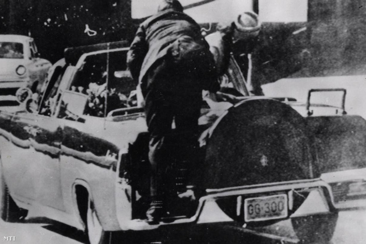 A lövés utáni pillanat: Mrs. Kennedy az ülésről alábukó férje után nyúl, egy ismeretlen férfi a kocsi lökhárítójára ugrik fel 1963. november 22-én