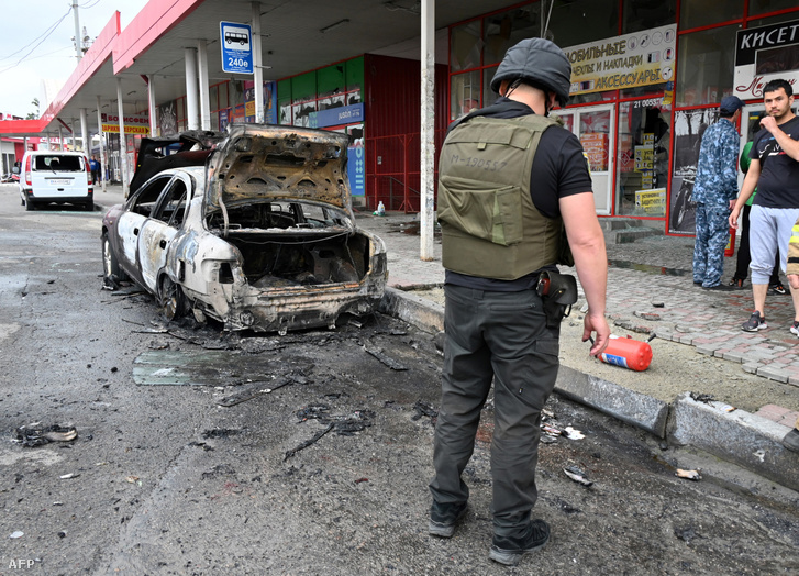 Rendőr áll egy leégett autó mellett 2022. július 21-én, miután orosz rakétacsapást mértek Harkivra