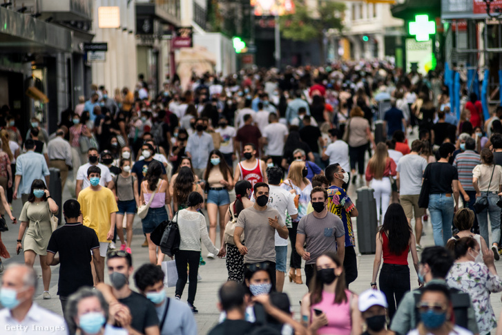 A koronavírus terjedésének megakadályozására arcmaszkot viselő tömeg sétál Madrid belvárosában 2021. június 6-án