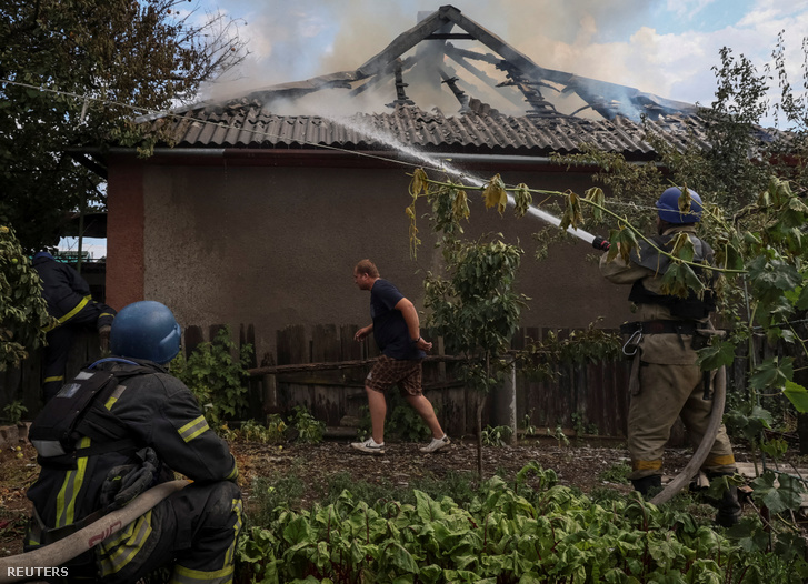 Tűzoltók oltják a tüzet egy bombatámadást ért ház előtt Ukrajnában 2022. július 9-én