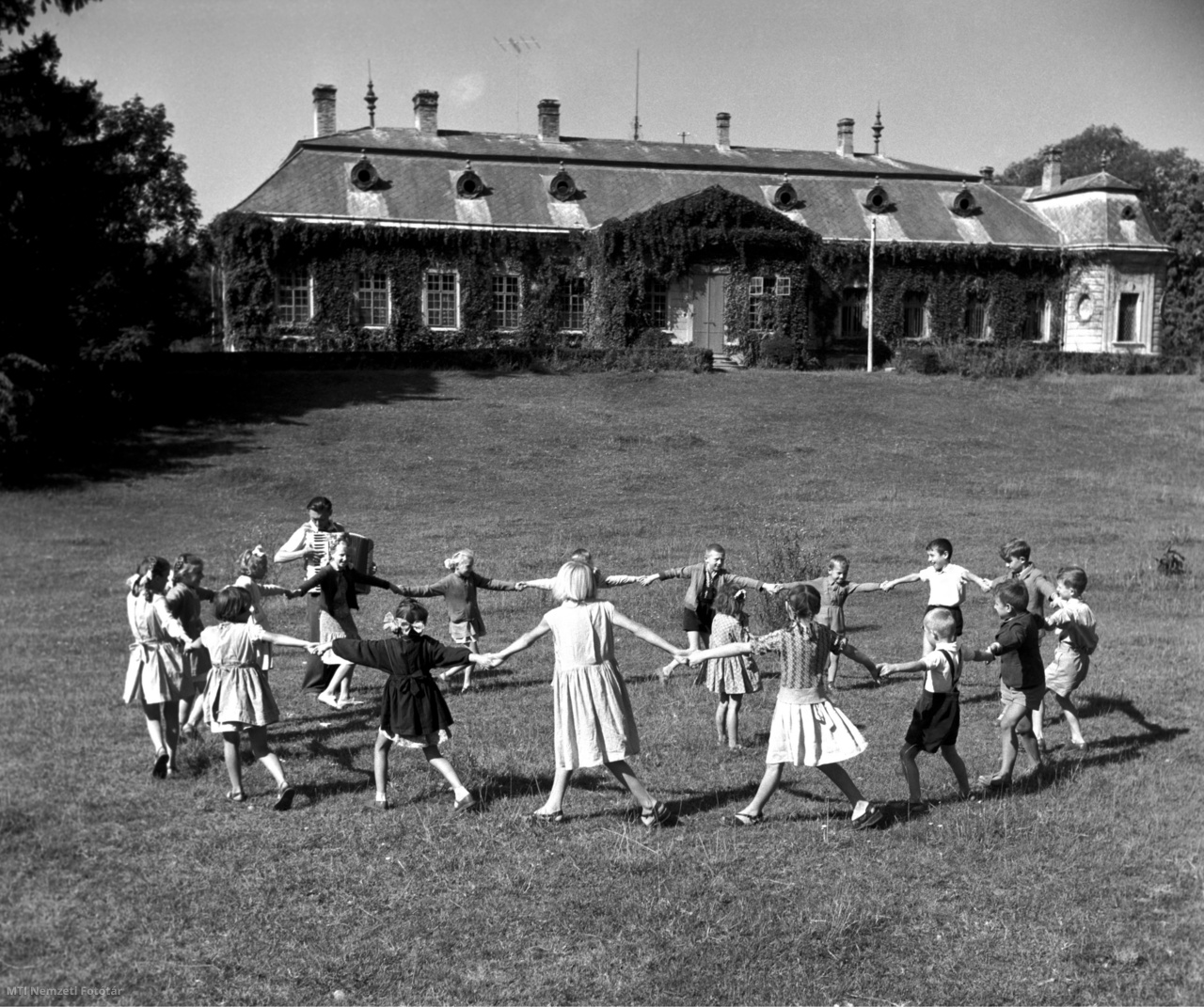 Tengelic, 1958. szeptember 2. Balla Tibor tanító tangóharmonikával kíséri a tengelici Petőfi Termelőszövetkezet általános iskolája diákjainak körjátékát az első tanítási nap szünetében