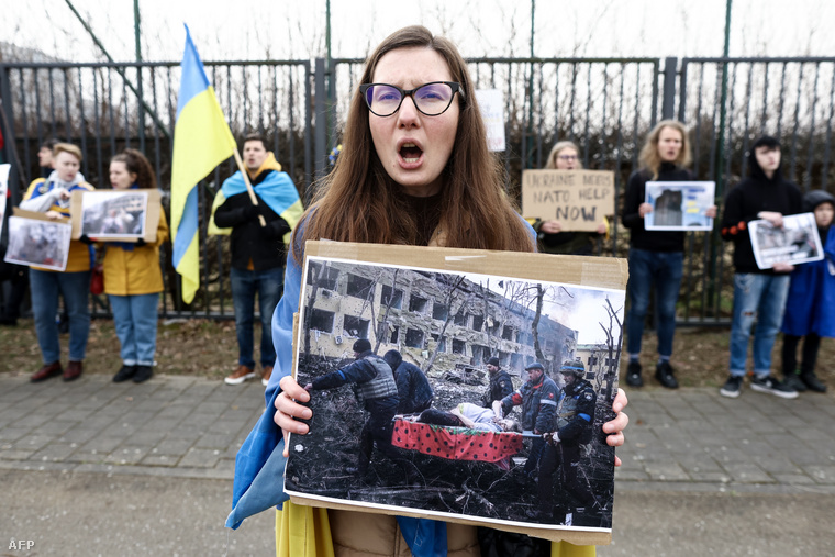 Egy az orosz invázió ellen tiltakozó nő, kezében a mariupoli szülészeti klinika lebombázását ábrázoló fotóval.