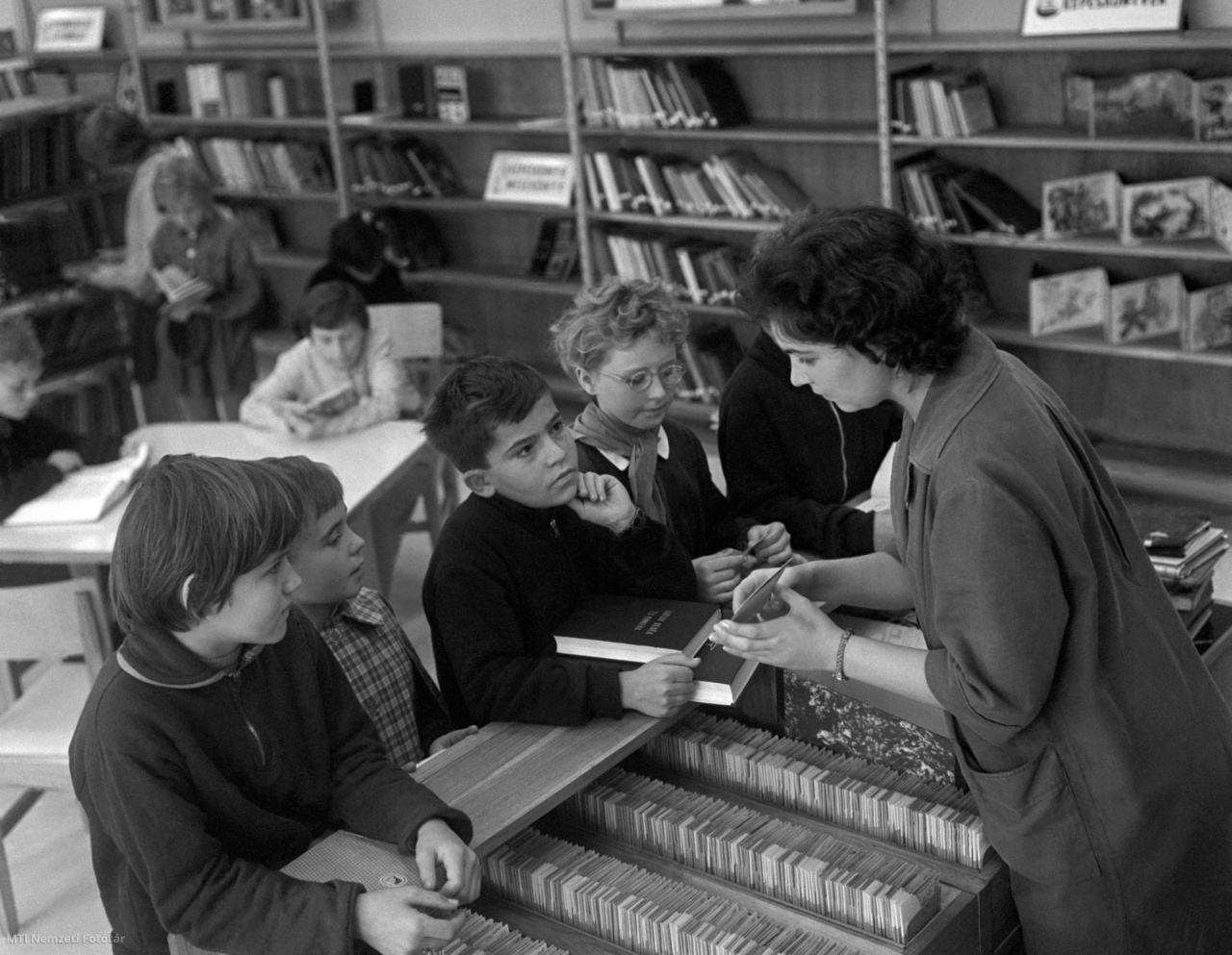 Tatabánya, 1964. október 13. Gyerekek beszélgetnek a könyvtárossal a Körner László Kossuth-díjas építőművész által tervezett, az ország egyik legkorszerűbb könyvtárának gyermekrészlegén. A földszintes, pavilonrendszerű könyvtár tágas, világos helyiségeiben szabad polcos felnőtt-, ifjúsági és gyermekrészleget rendeztek be, és mintegy százezer kötet áll az olvasók rendelkezésére