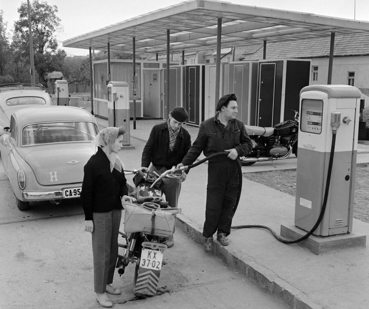 Eger, 1961. október 13. Férfi üzemanyagot tölt egy nő motorkerékpárjába Észak-Magyarország legkorszerűbb benzinkútjának töltőállomásán. A benzinkúton az autósok és motorosok öt kútoszlopból tankolhatnak, a tartályok 125 000 liter benzin állandó tárolására alkalmasak (/MTI Nemzeti Fotótár)