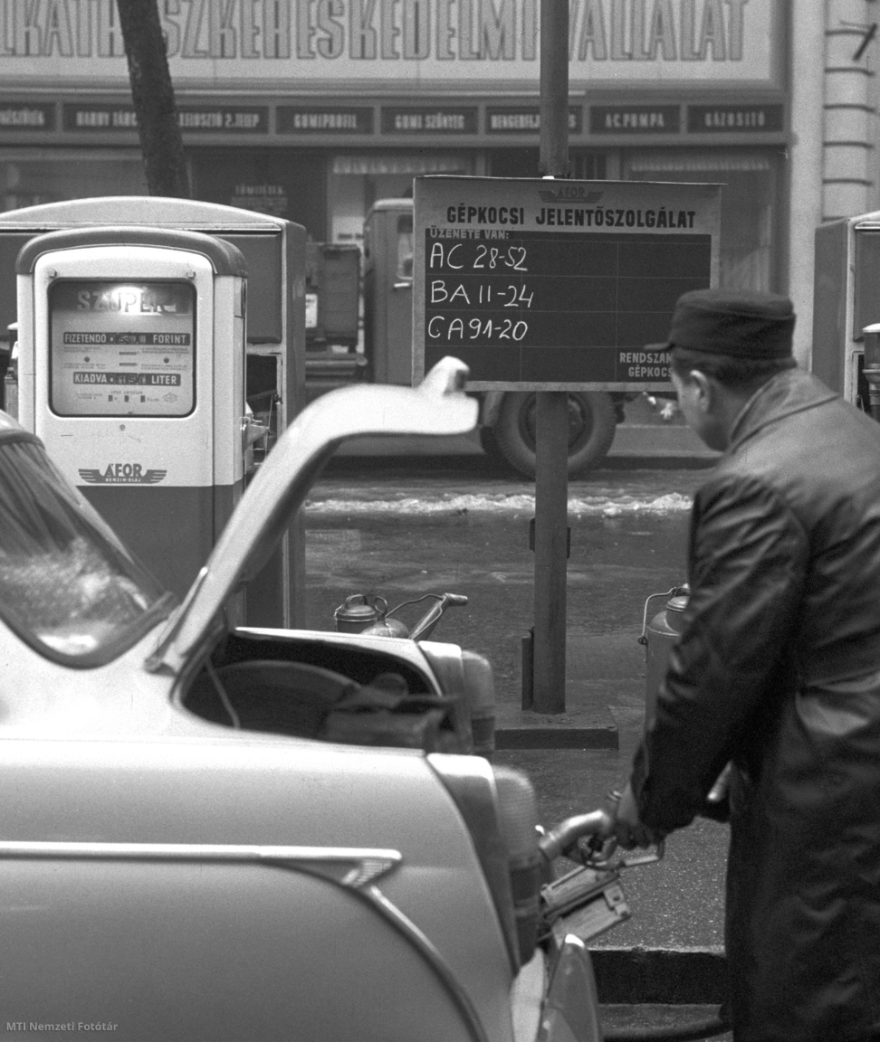 Budapest, 1963. január 7. Férfi üzemanyagot tankol az autójába, közben az üzenetközvetítő táblát nézi a Liszt Ferenc téri ÁFOR-benzinkútnál. A próbaképpen létesített üzenetközvetítő táblákon üzenhetnek a rendszám alapján a gépkocsivezetőknek (/MTI Nemzeti Fotótár)