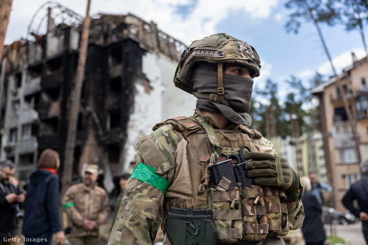 Egy ukrán katona áll őrt a megsérült Irpinsky Lipky lakókomplexumnál 2022. április 28-án
