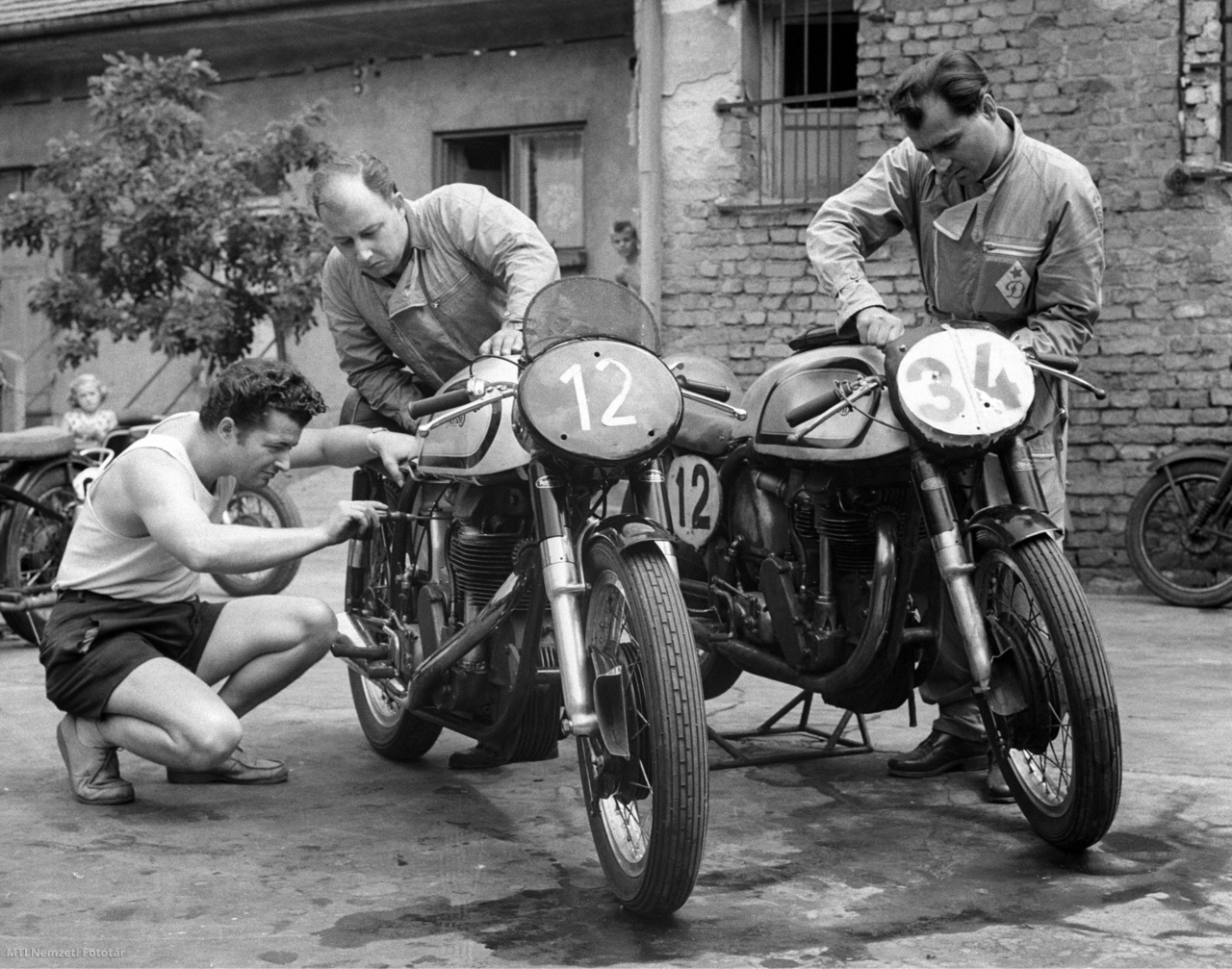 1959. július 30. Királyföldi László, Cserkuti László és Pásztor István motorversenyzők (b–j) szerelik motorkerékpárjaikat, hogy felkészüljenek a vasárnap megrendezésre kerülő Grand Prix-versenyre. A felvétel készítésének pontos helye ismeretlen.
