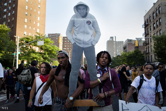 A Trayvon Martin meggyilkolásával vádolt George Zimmerman bírósági felmentése miatt tiltakoznak tüntetők a New York-i Manhattan negyedben 2013. július 14-én. A 17 éves áldozatot ábrázoló kép feliratának jelentése: „Mindannyian Trayvon Martin vagyunk”.
