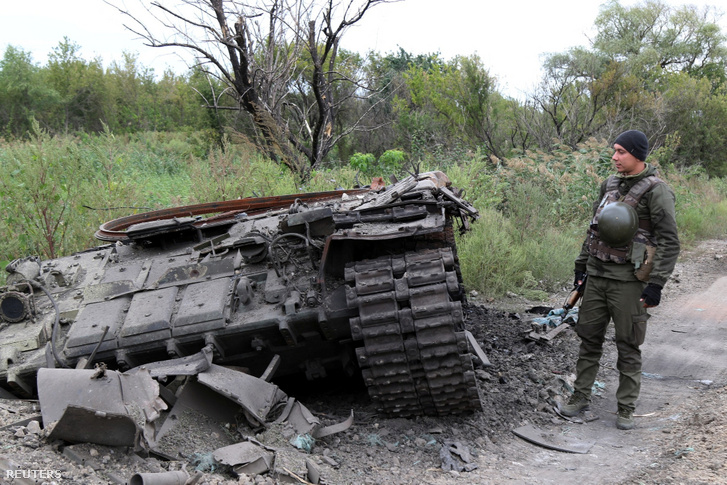Ukrán katona egy kilőtt orosz tank mellett a harkivi régióban