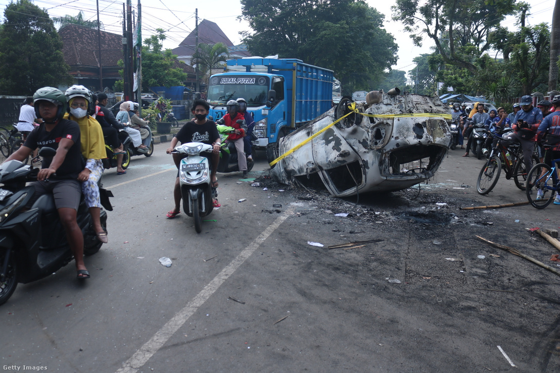 Emberek haladnak el egy megrongált rendőrautó mellett Malang városában 2022. október 2-án