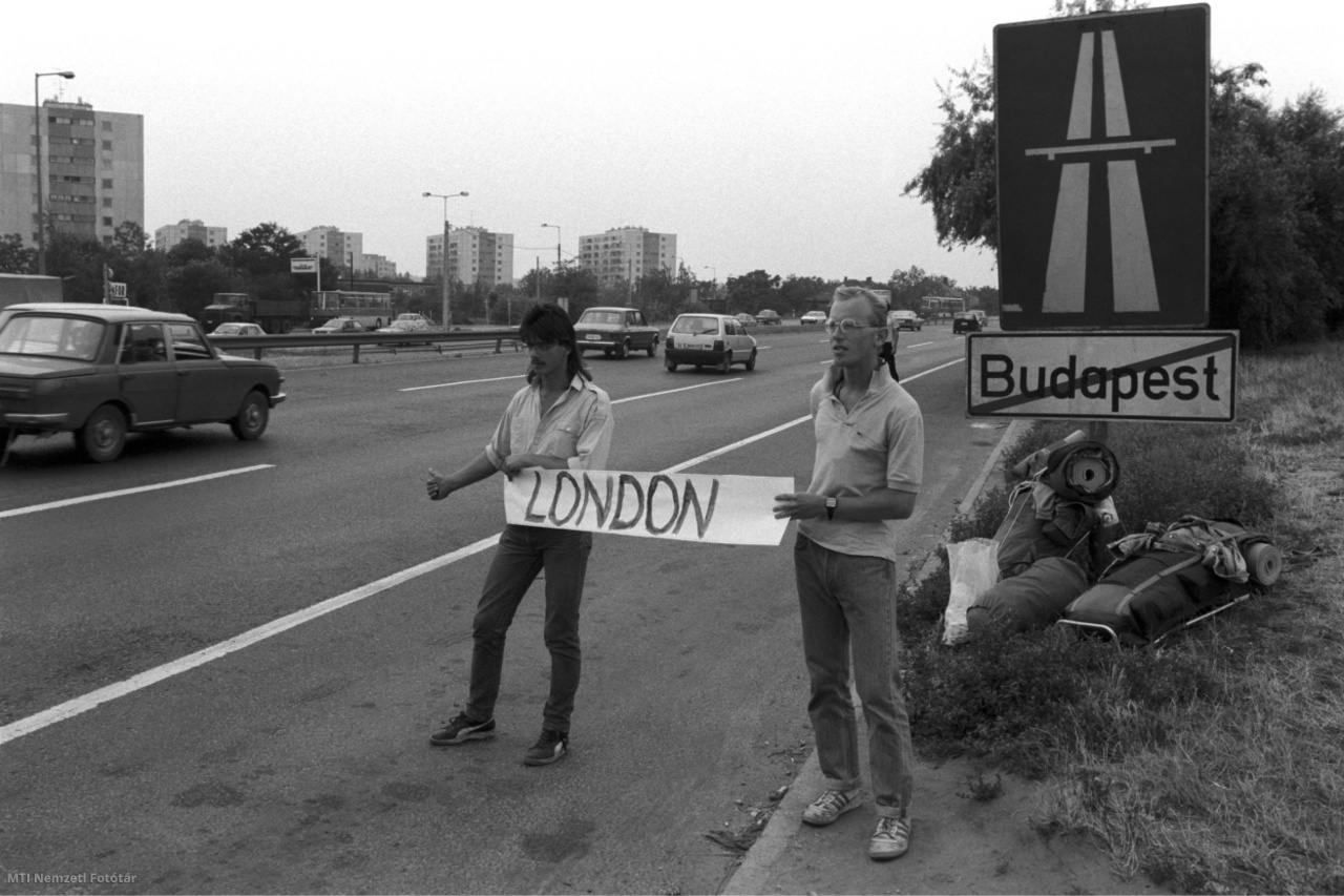 Budapest, 1990. július 27. Lustyik János elektroműszerész (b) és Egri Ferenc egyetemi hallgató, akik autóstoppal akarnak eljutni Nagy-Britanniába, London feliratú táblát tartanak az M7 autópálya kivezető szakaszánál.
