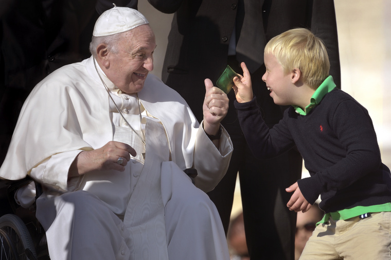 Ferenc pápa egy gyermek társaságában mosolyog.