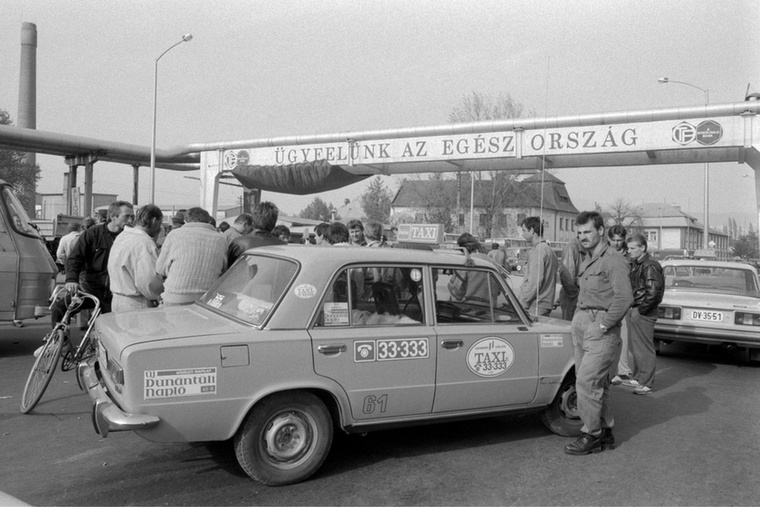 Tiltakozó taxisok állnak egyikük autója mellett a benzináremelések ellen tartott tiltakozó demonstráción a Pécsről Harkány felé vezető úton