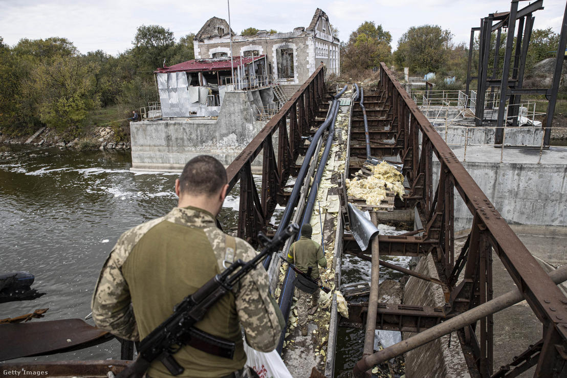 Ukrán katonák kelnek át a megsérült hídon, amely a Herszon régióban található