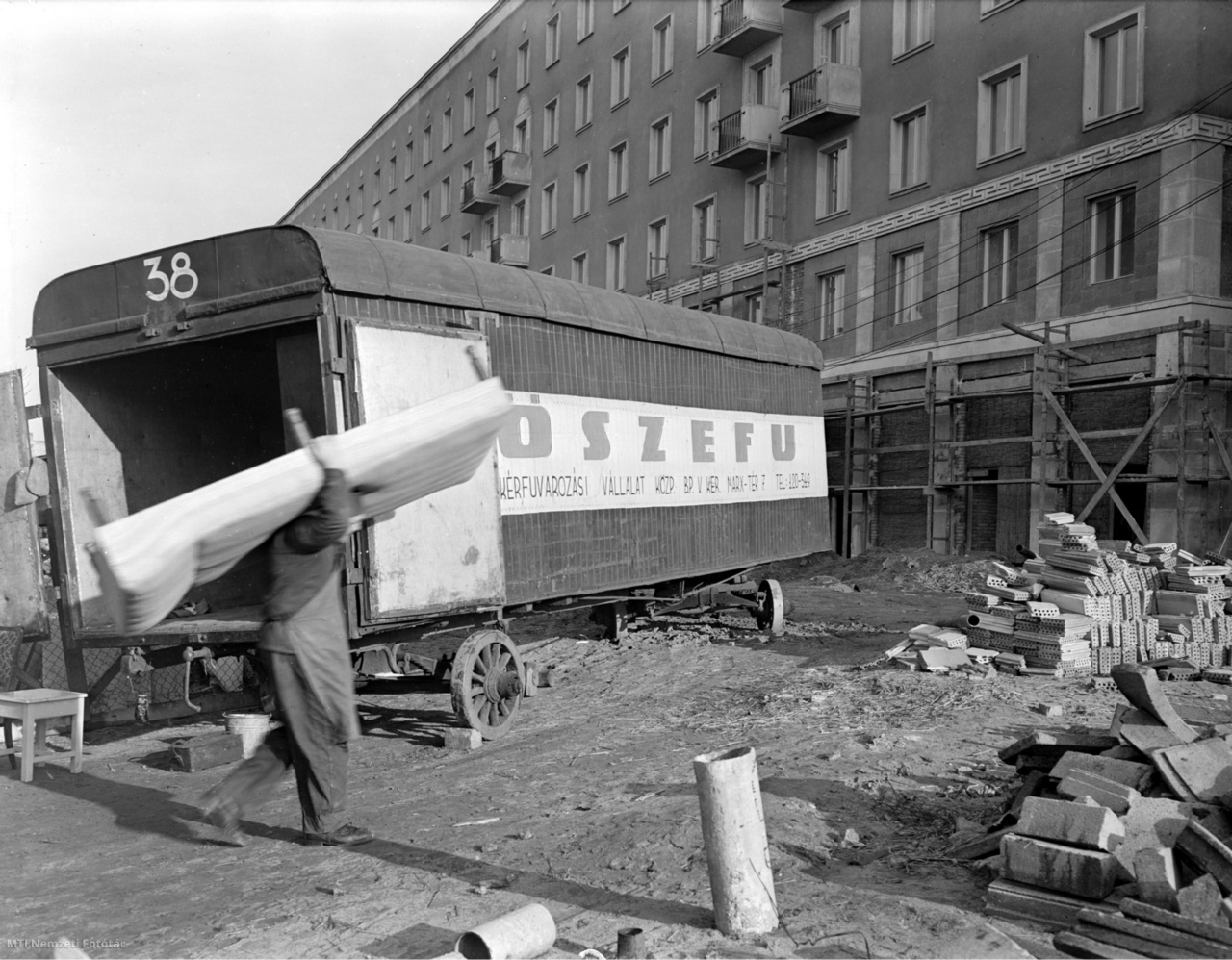 Budapest, 1956. január 2. Munkás pakolja ki a bútorokat a Fővárosi Szekérfuvarozási Vállalat teherkocsijából a X. kerületi Kőrösi Csoma Sándor út és Harmat utca sarkán épült lakóháznál, ahová beköltözik a lakók első csoportja