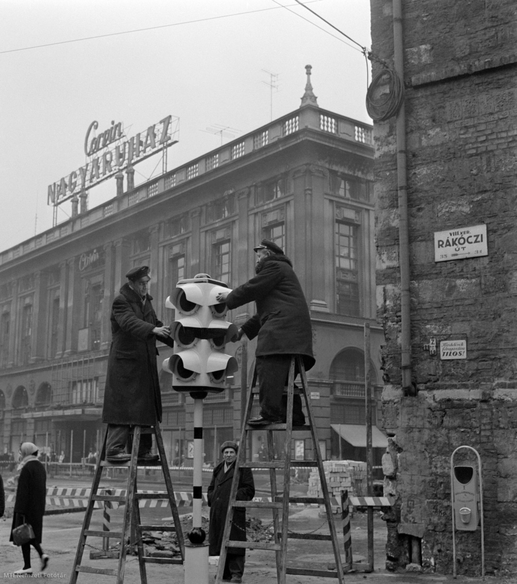 Budapest, 1964. február 27. Szakemberek forgalmi jelzőlámpát szerelnek a Rákóczi úton, a Klauzál utca találkozásánál a Blaha Lujza térnél lévő gyalogos átkelőhelynél. A háttérben a Corvin Nagyáruház épülete.