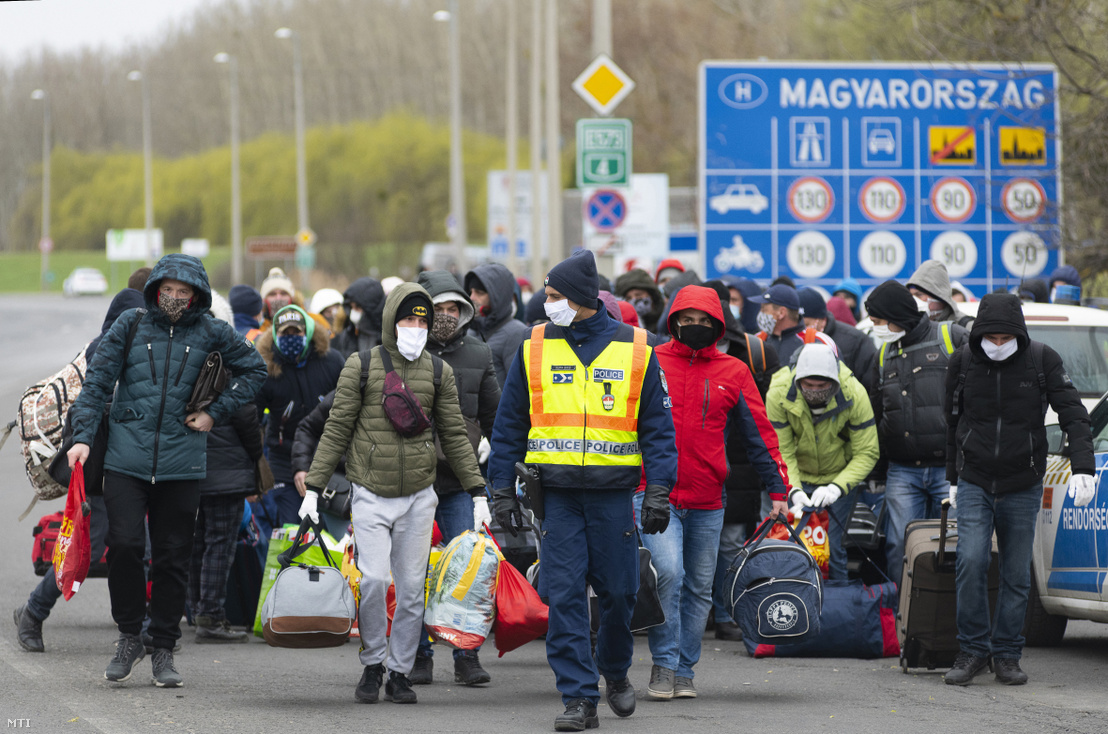 Európai országokban vendégmunkásként dolgozó, a koronavírus-járvány miatt hazautazó ukrán állampolgárok egy csoportját vezeti fel egy rendőr a záhonyi magyar–ukrán határátkelőhelyre 2020. március 30-án