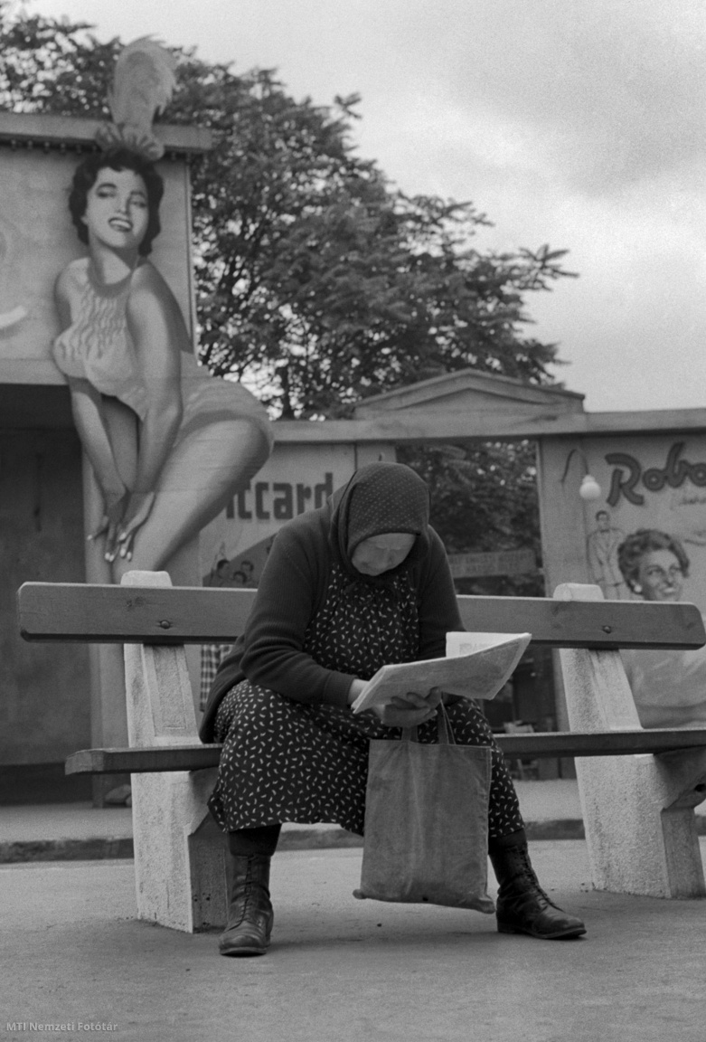 Budapest, 1960. július 12. Idős nő padon ülve újságot olvas a Városligetben, mögötte az épület bejáratánál álló, női alakot formázó, nagy méretű díszlet a Fővárosi Nagycirkuszt hirdeti.