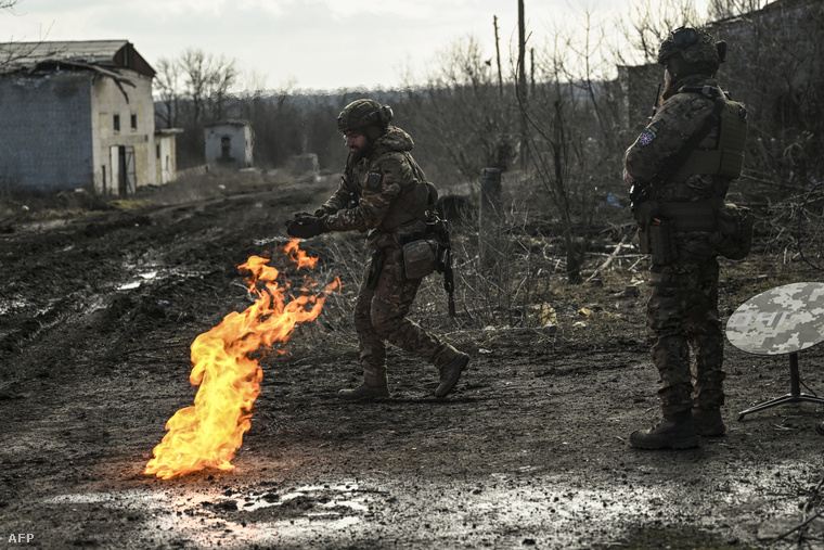Ukrán katonák puskaporral begyújtott tűznél melegszenek Bahmut közelében a Donbasz régióban, 2023