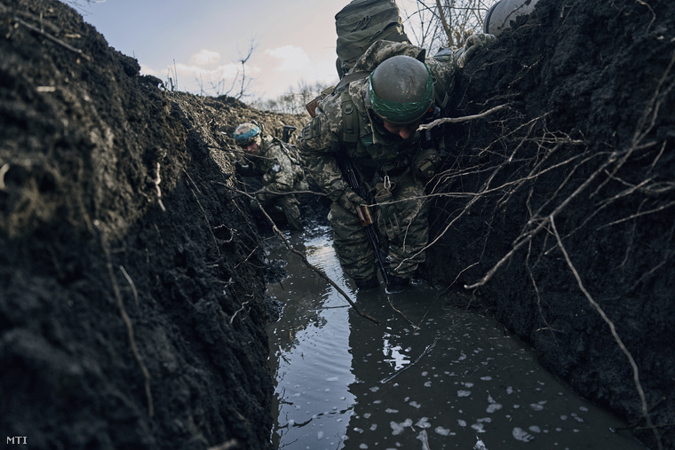 Ukrán katonák egy vízben álló lövészárokban gázolnak a donyecki régióban fekvõ ostromgyûrûben lévõ Bahmutnál, 2023