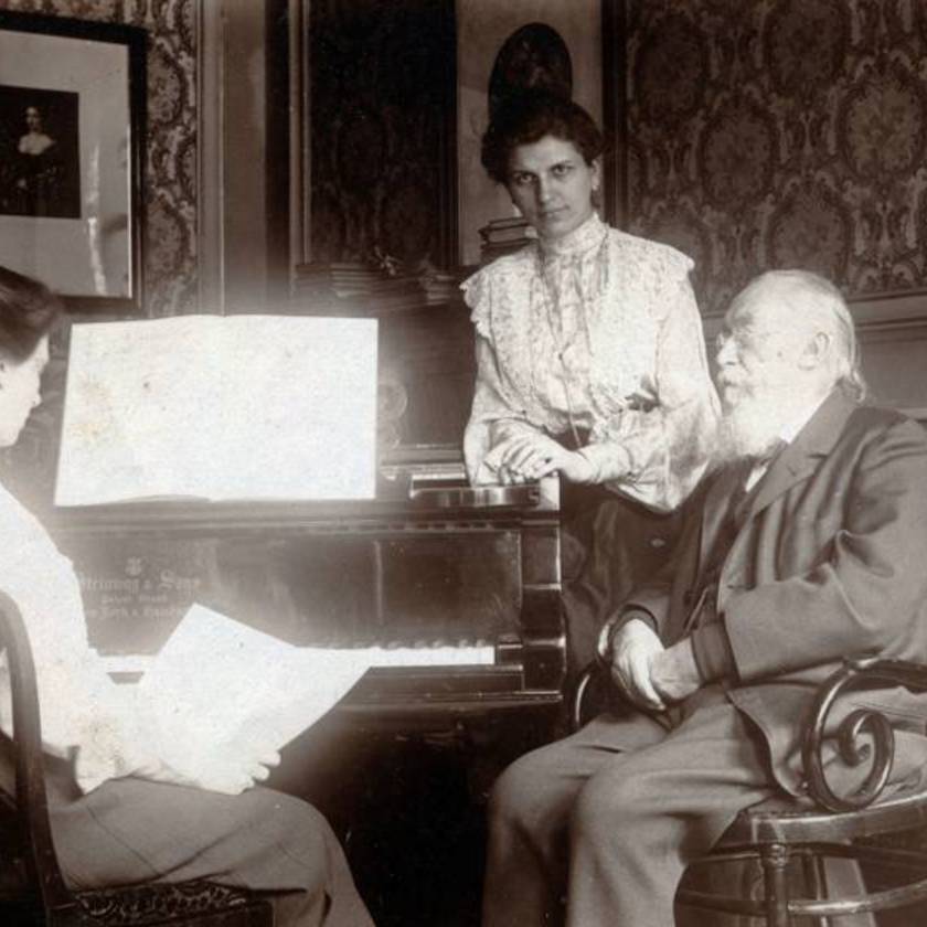 A fotó 1913-ban készült. A főúri és polgári családokban is szokás volt, hogy a kisasszonyok zenét tanulnak. Itt épp egy zongoraleckének lehetünk szemtanúi, ami egy gyönyörű szalonban zajlott.