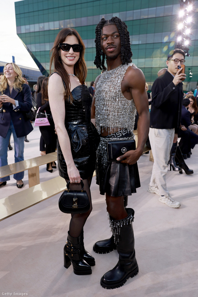 Anne Hathaway tetőtől talpig Versace kiegészítőkben tette tiszteletét: a szettje fekete krokodil hatású miniruhából, áttetsző harisnyából, aranycsattos bőrcsizmából, és egy hozzáillő kis pénztárcából állt