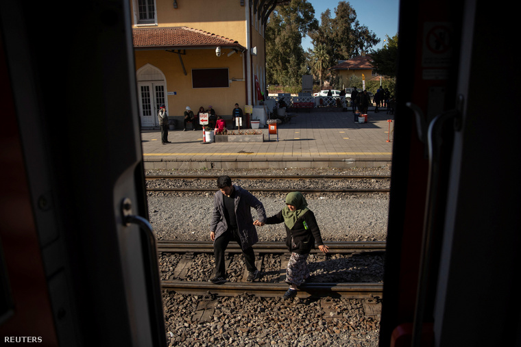 Egy férfi és egy nő megy át a síneken Iskenderun pályaudvarán, ahol a kocsikat ideiglenes menedékhelyekké alakították át a február 15-i földrengés után