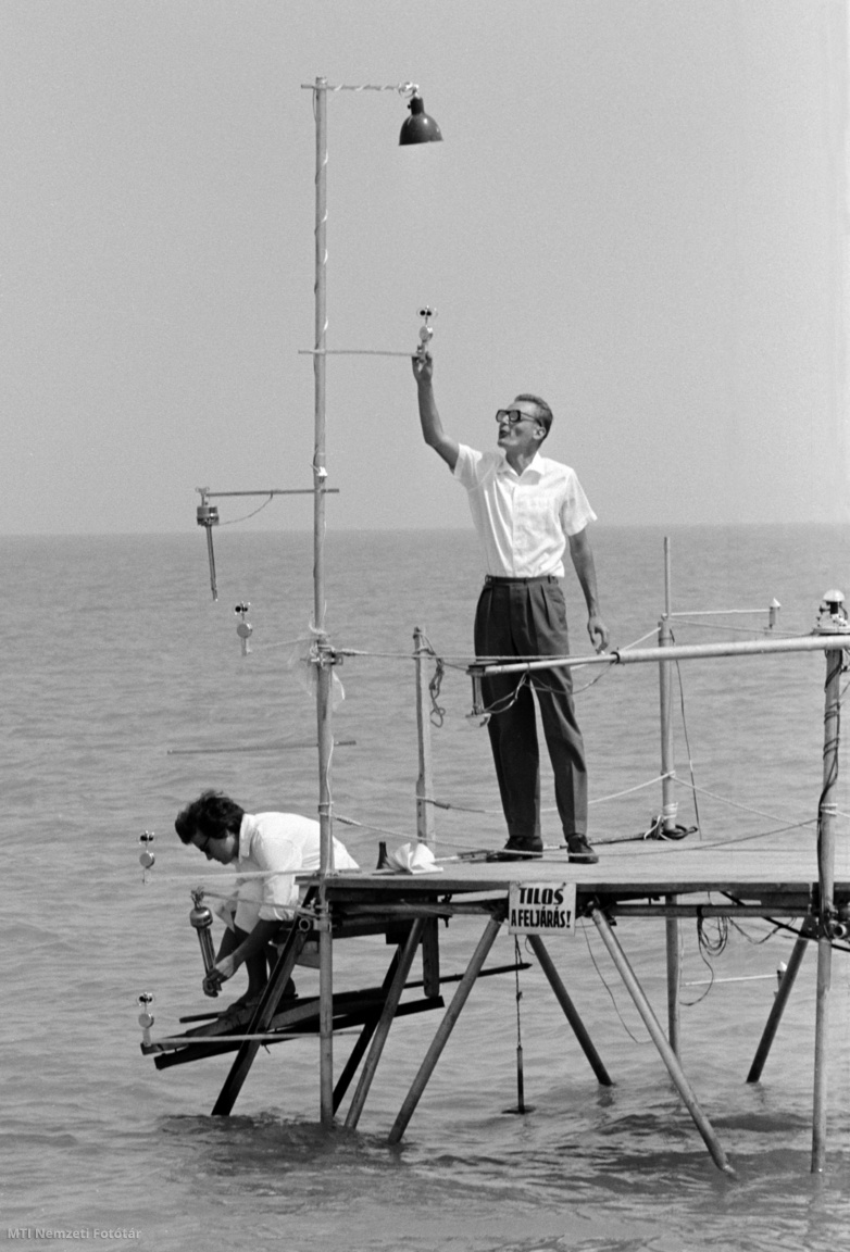 Siófok, 1962. augusztus 1. Endrődi Gabriella és Götz Gusztáv, a Meteorológiai Intézet siófoki obszervatóriumának tudományos munkatársa a Balatonkutató Állomás vízre épített észlelőállomásának műszereit ellenőrzi. A kutatók a mindenkori időjárással kapcsolatban figyelik a Balaton és közvetlen környezete speciális meteorológiai viszonyait. Az észlelőállomásokon több szintben mérik a szélsebességet, a levegő és a talaj hőmérsékletét, nedvességét, a beérkező és visszavert sugárzást, valamint a vízhőmérsékletet, és első alkalommal hasonlítják össze a balatoni vízfelszín és a szárazföld feletti meteorológiai viszonyokat
