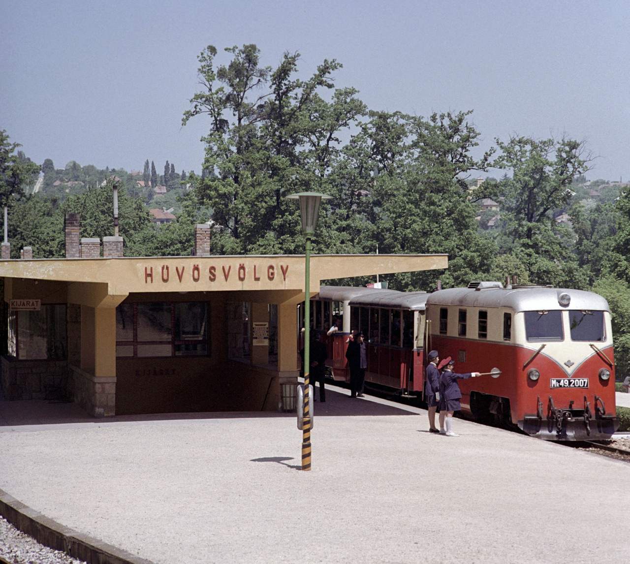 Budapest, 1967. május 28. Úttörő naplózó forgalmi szolgálattevő meneszti a vonatot az Úttörővasút hűvösvölgyi végállomásáról. Több mint egy évtizede közlekedik a Széchenyi-hegy és a Hűvösvölgy között a fiatalok vonata, az Úttörővasút. A forgalmi teendőket a budapesti iskolák mintegy 600-700, jeles és jó előmenetelű tanulójából összeállított 15 csapat látja el. A 11,2 kilométer hosszúságú, hegyek között kanyargó pálya nyolc állomásán egyszerre 30 úttörővasutas teljesít szolgálatot. Felnőtt állomásfőnök felügyeletével a jegykiadástól kezdve a teljes forgalmi rend minden teendőjét ők látják el. A vasutat nemcsak a gyermekek, hanem a felnőttek is szívesen látogatják, egy-egy nyári vasárnapon 10-15 ezer utast is szállítanak az ezüst-piros színre festett vonatok. A csapatok tagjai egész éves jól végzett munkájukért nyaranta két hetet a Csillebérci Úttörőtáborban tölthetnek el