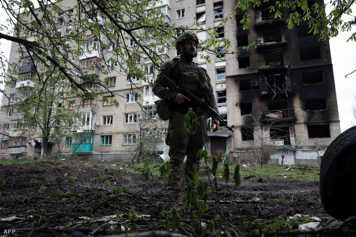 Ukrán katona egy megsérült lakóépület előtt Bahmutban 2023. április 23-án