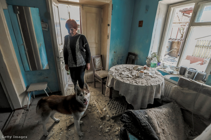 Egy nő kutyájával Herszonban, miután házát bombatalálat érte 2023. április 18-án